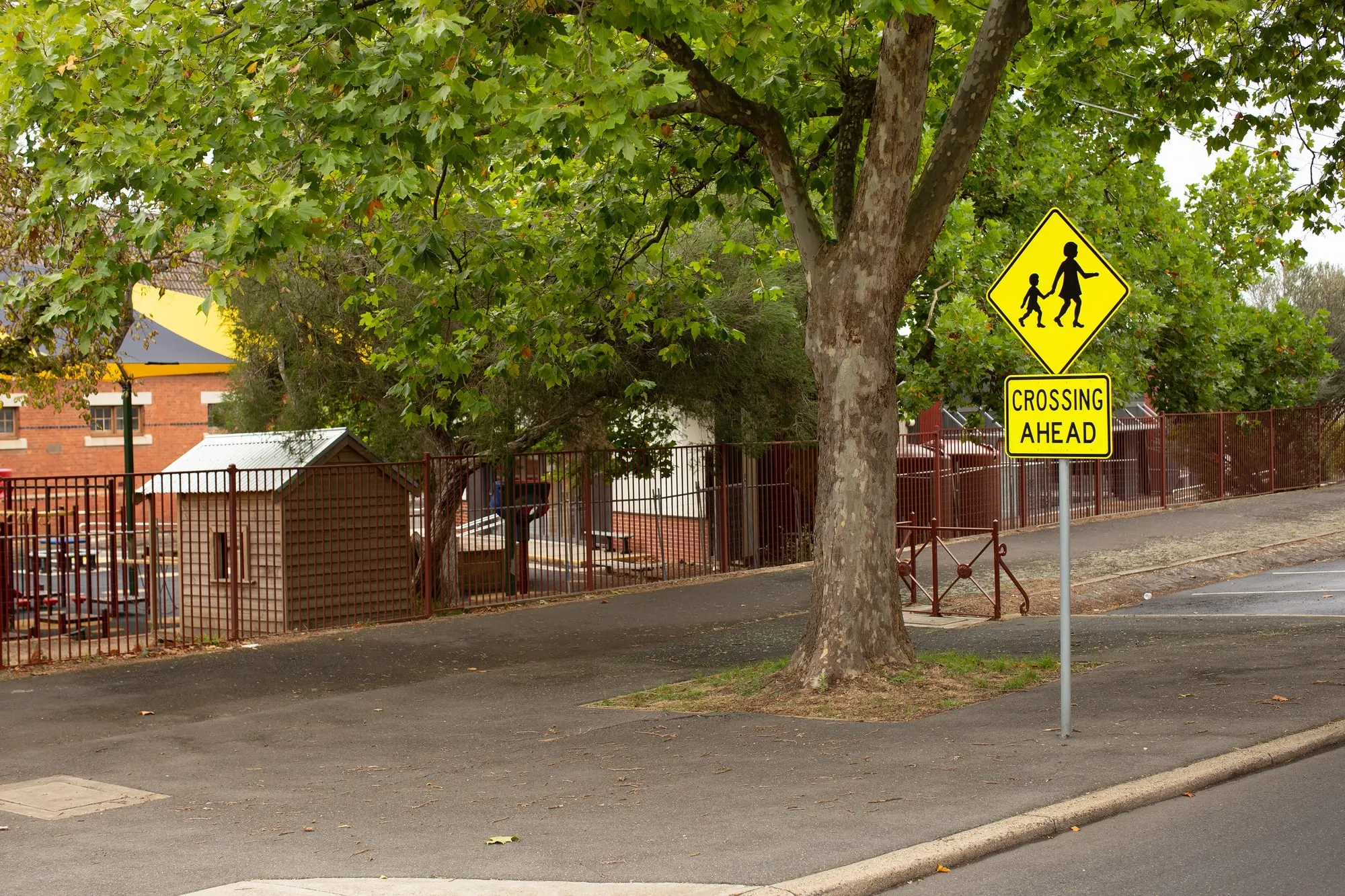 A children's crossing sign on the street outside a suburban school.